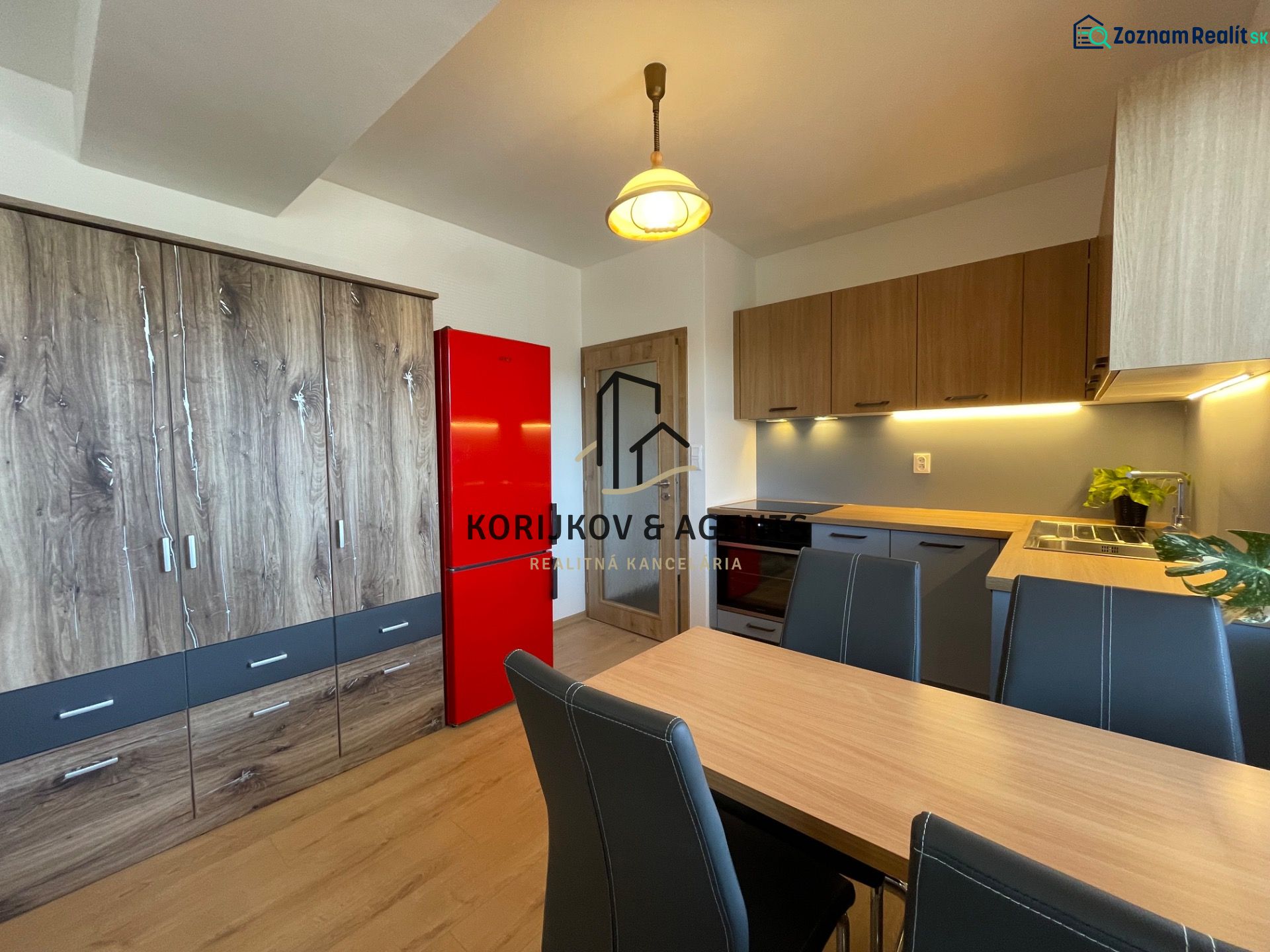A kitchen in a 2-room apartment with cabinets featuring a wooden decor and a red refrigerator.