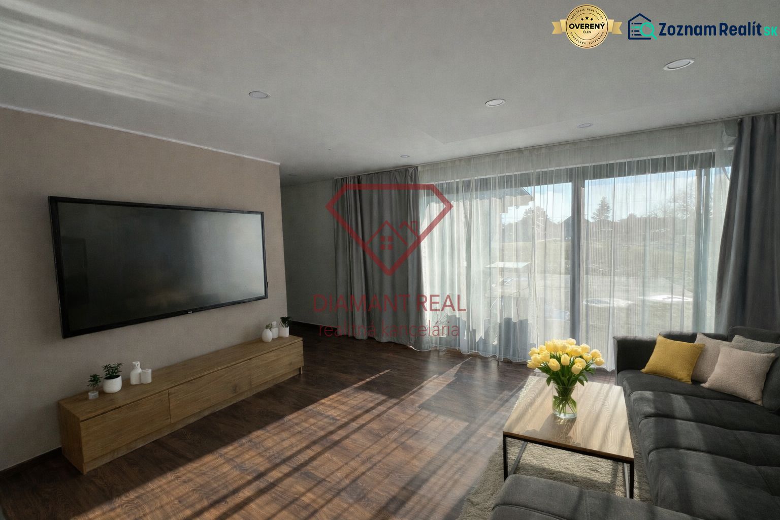 Living room in a family house with a large television, sofa, and wooden decor flooring.