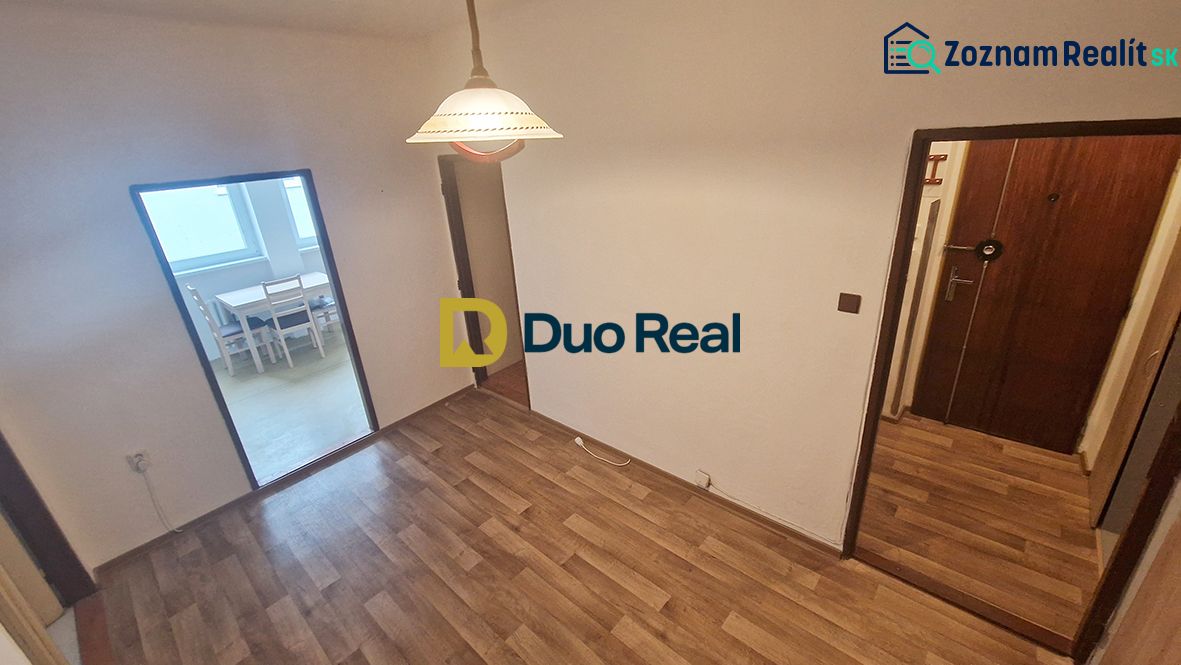 A room with a wooden decor floor, entrance door, and dining area in a 3-room apartment.