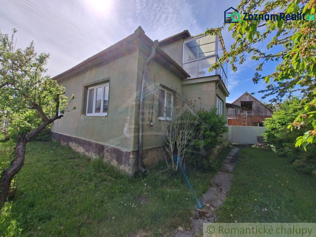 A family house in Orešany with a green exterior and a garden, surrounded by trees.