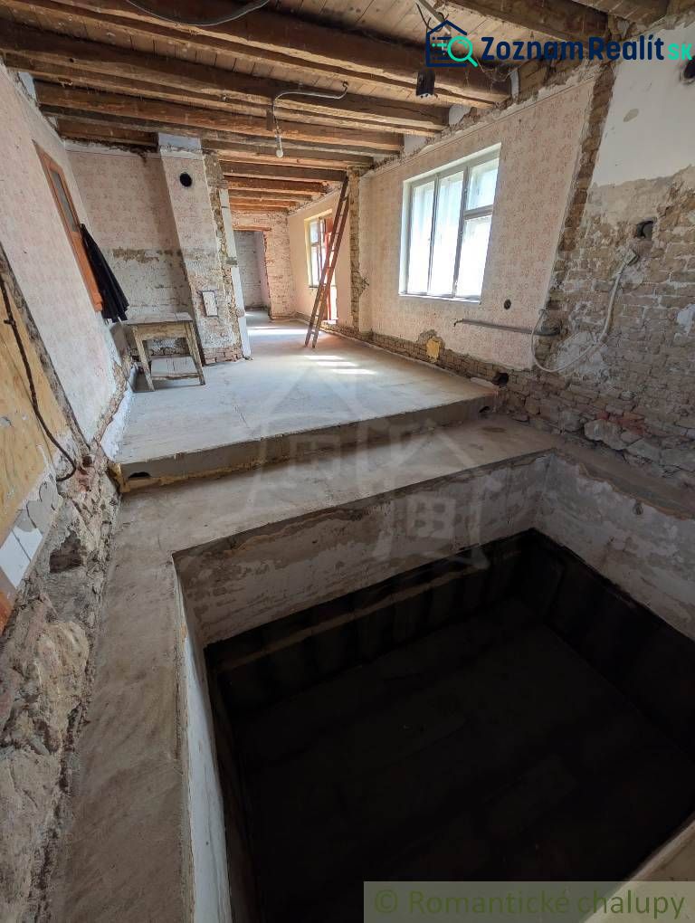 Interior of a family house with an exposed ceiling and raw walls under renovation.