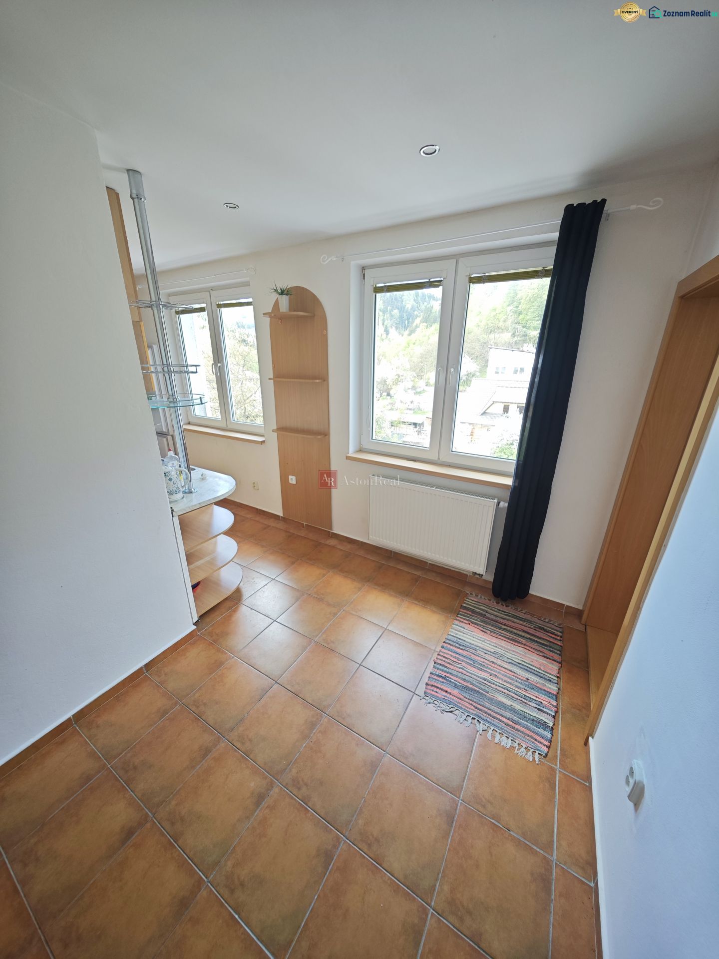 A room in a 3-room apartment with tiles, windows, and shelves.