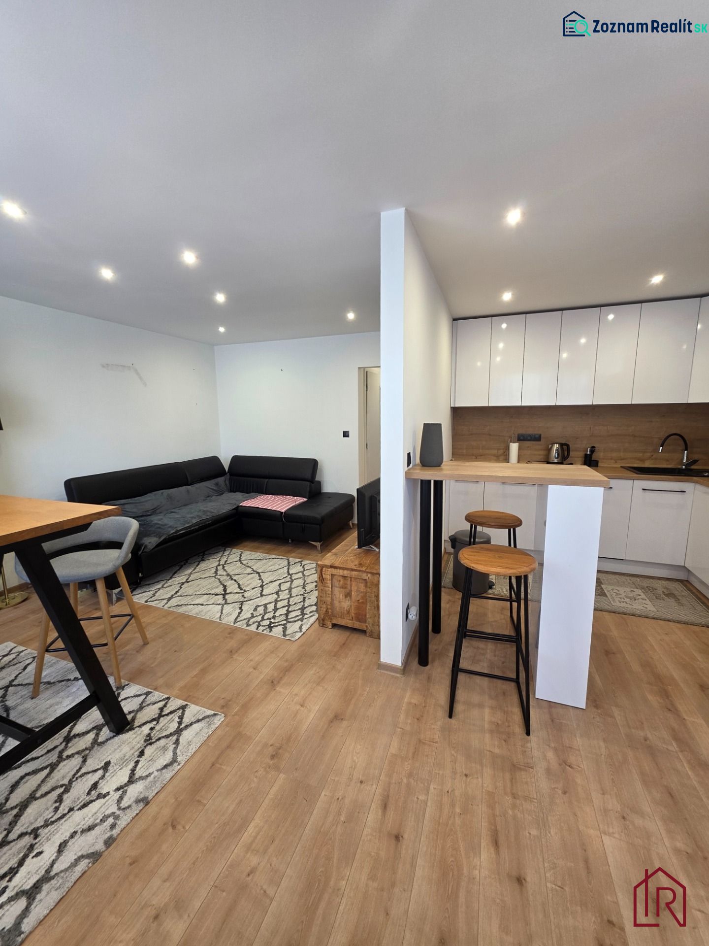 Living room with kitchen in a 3-room apartment, wooden decor flooring, sofa set.