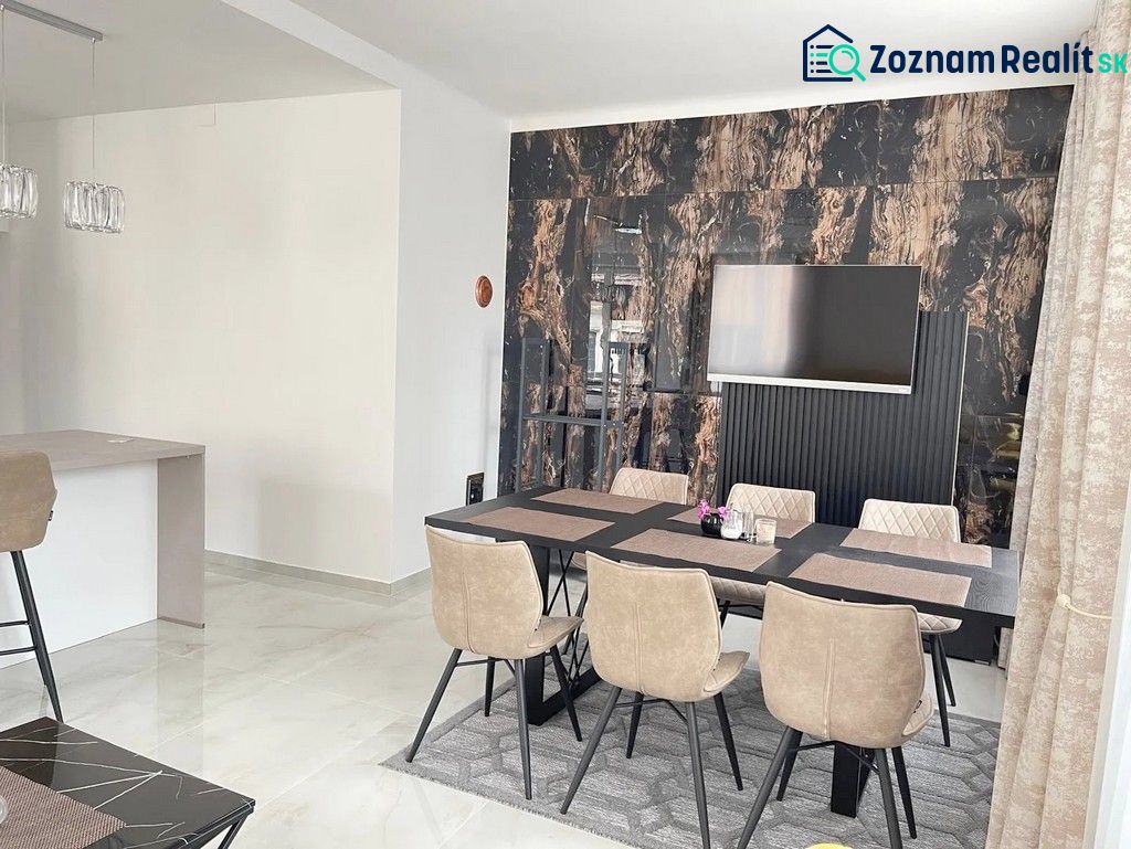 Dining room with a table and six chairs, wooden decor flooring, TV on the wall.