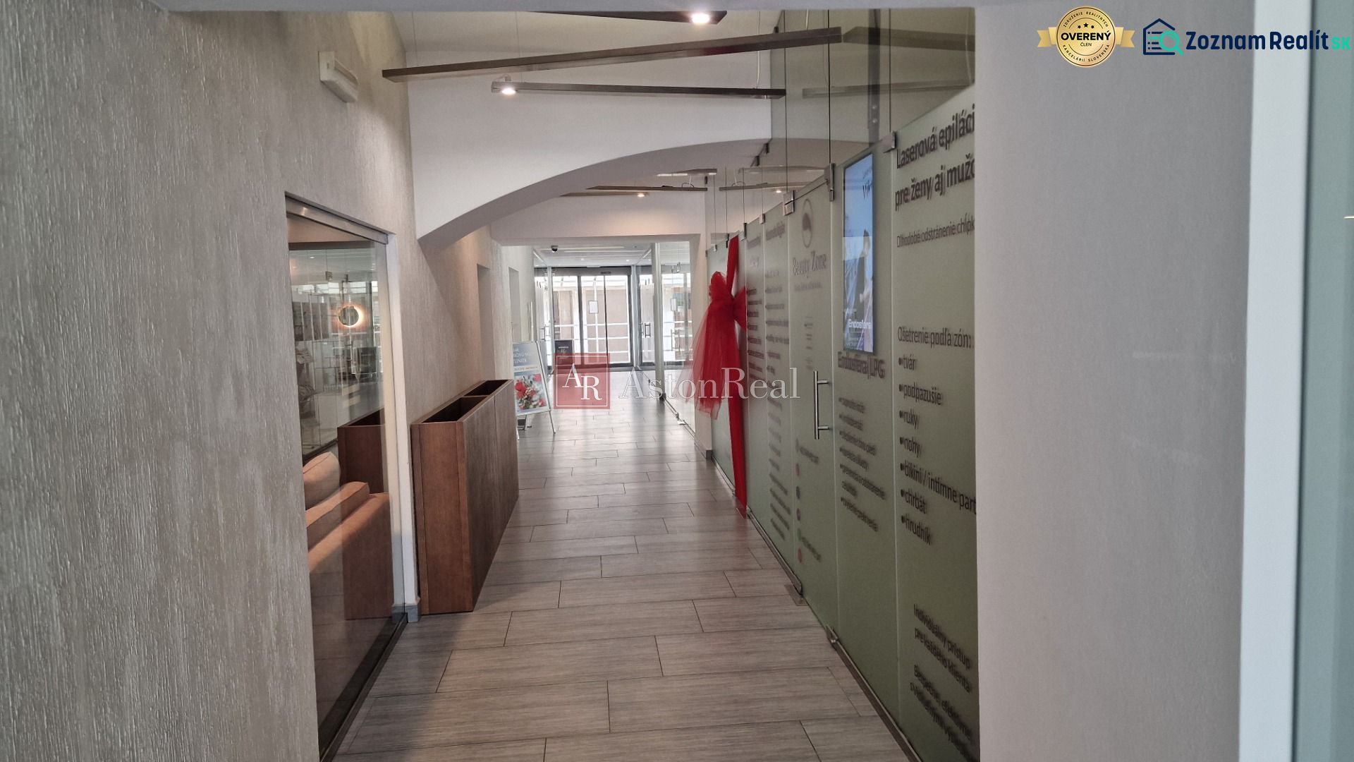 Interior of commercial premises with a long corridor space, glass walls, and a light floor.