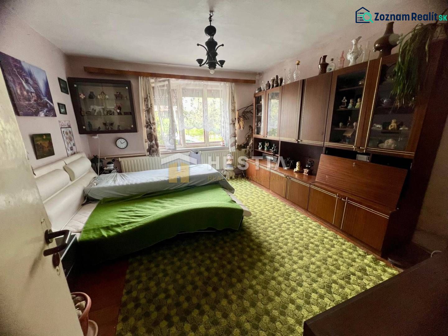 Bedroom in a family house with carpeted floor, wardrobe set, and large window.