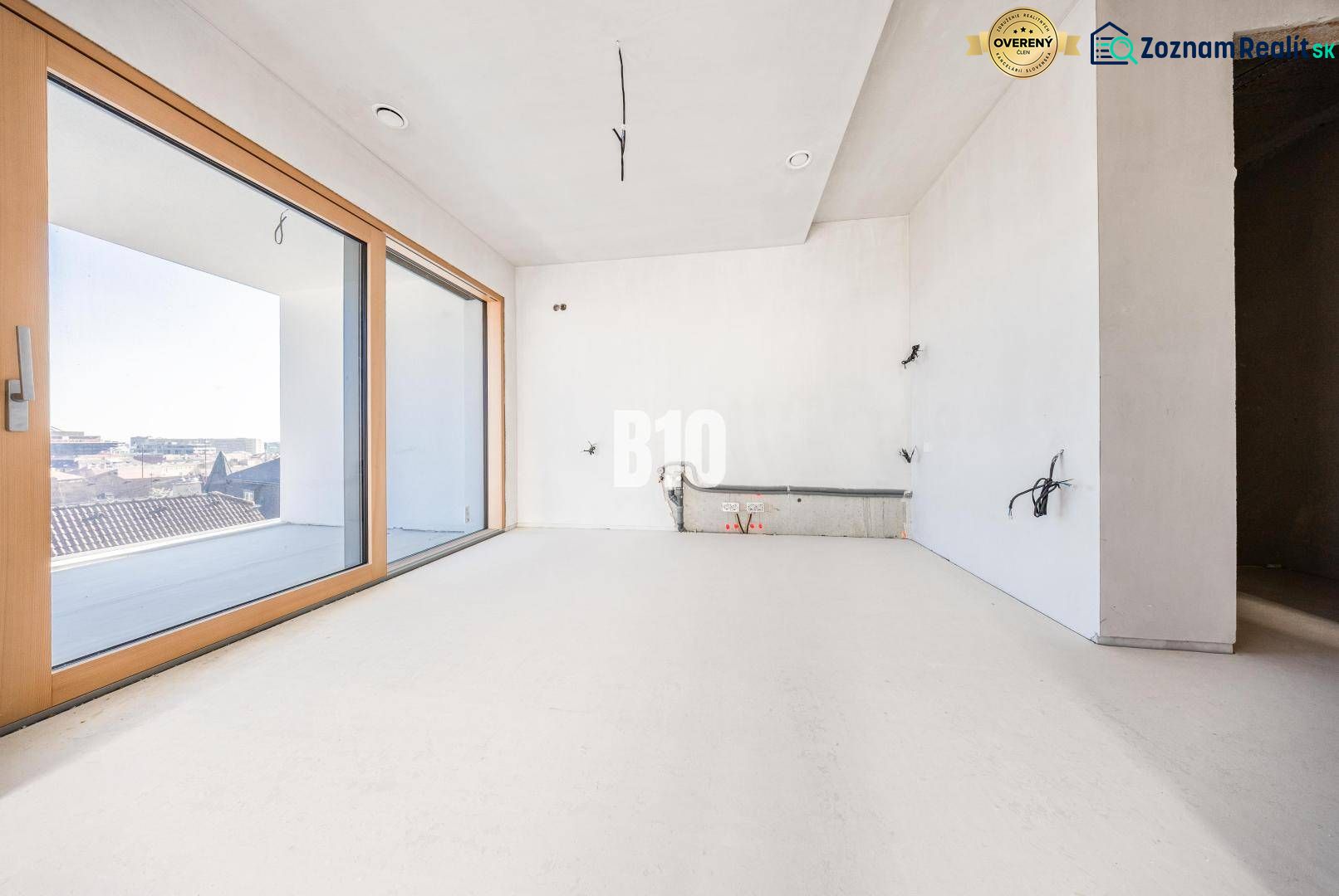A room with large windows and a wooden decor floor in a 3-room apartment.