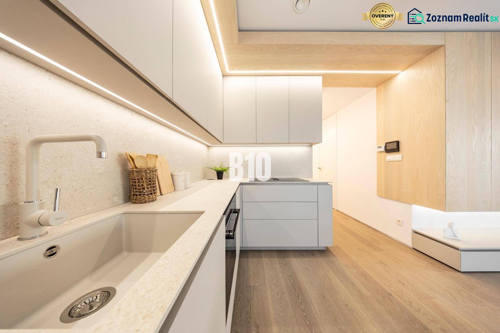 A kitchen in a 3-room apartment with a wooden decor floor and minimalist design.