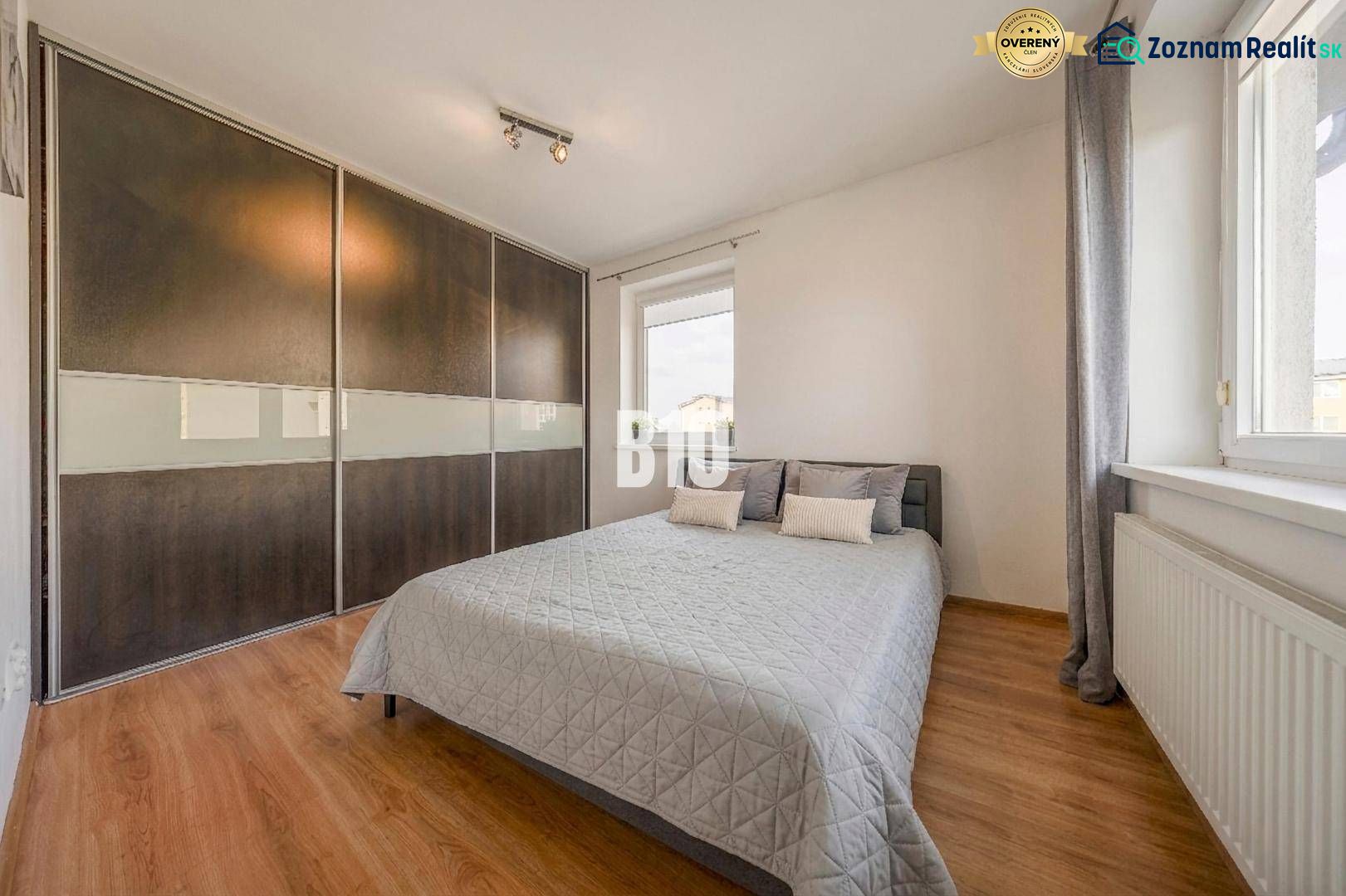 Bedroom in a 2-room apartment with a wood-patterned floor and a large built-in wardrobe.