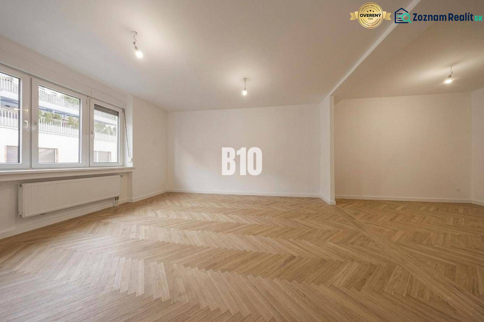 A spacious room with a wooden decor floor in a 3-room apartment.