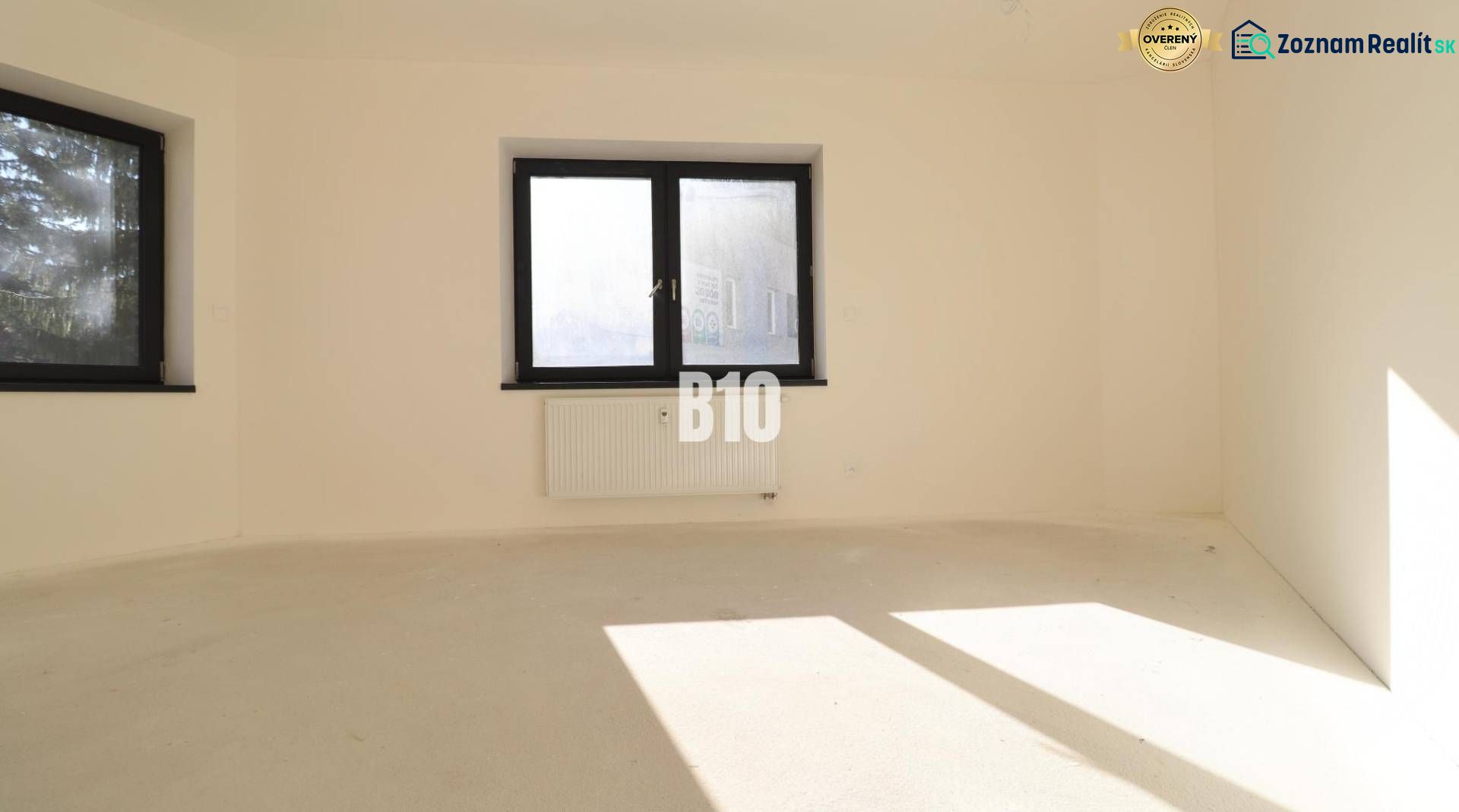 An empty office with two windows and a radiator, light walls, floor without wood decor.