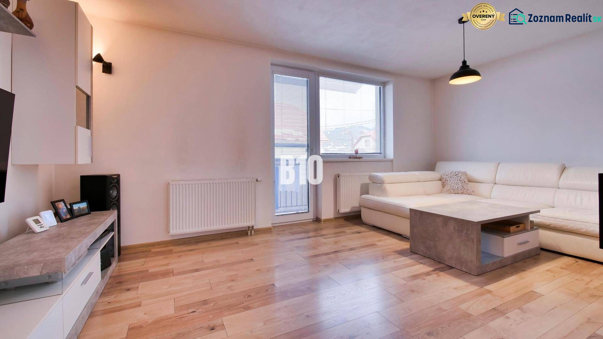 Living room in a 3-room apartment with a wooden decor floor and a white sofa.