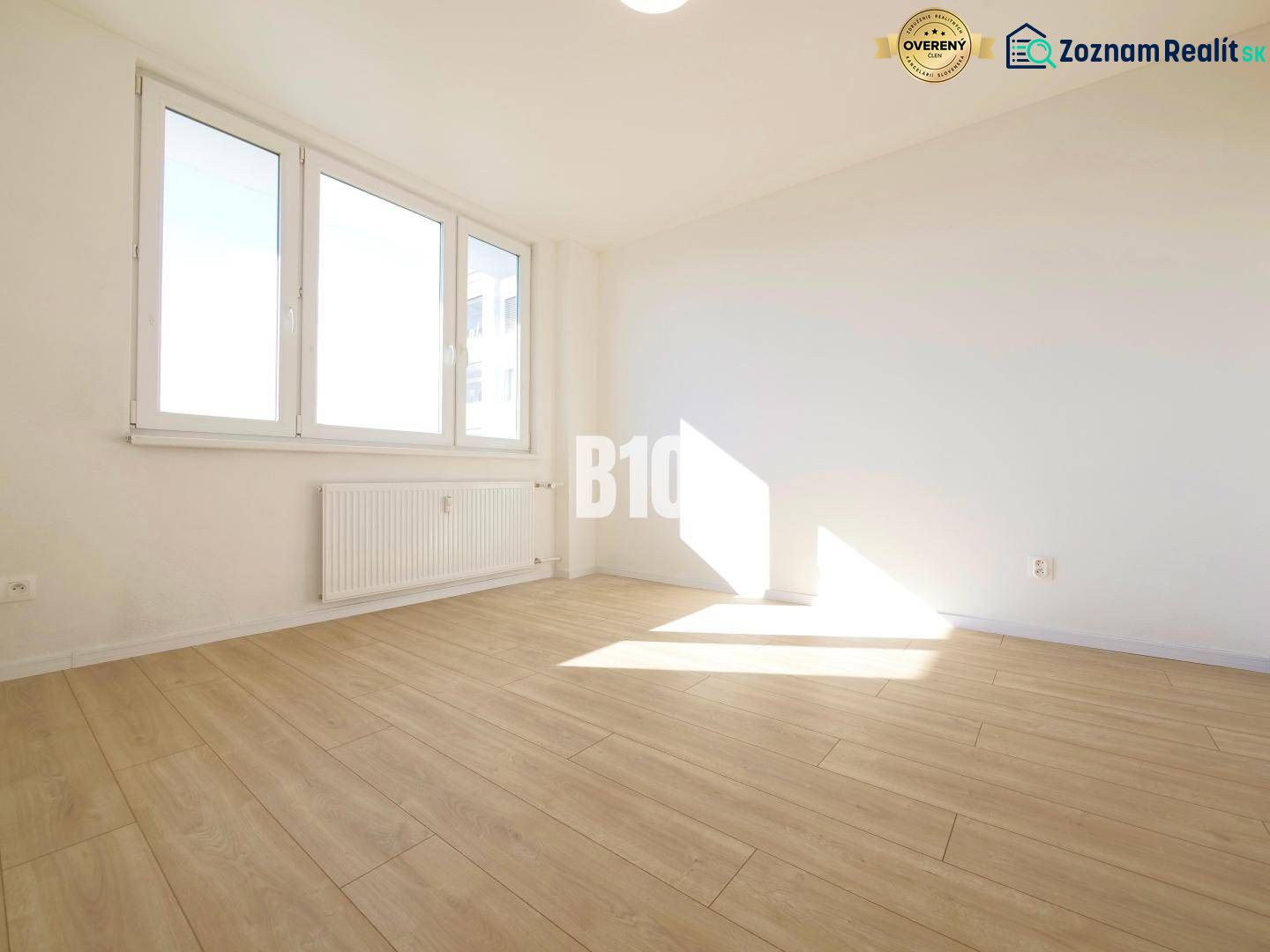 A room in a 3-room apartment with large windows and a floor with a wooden decor.