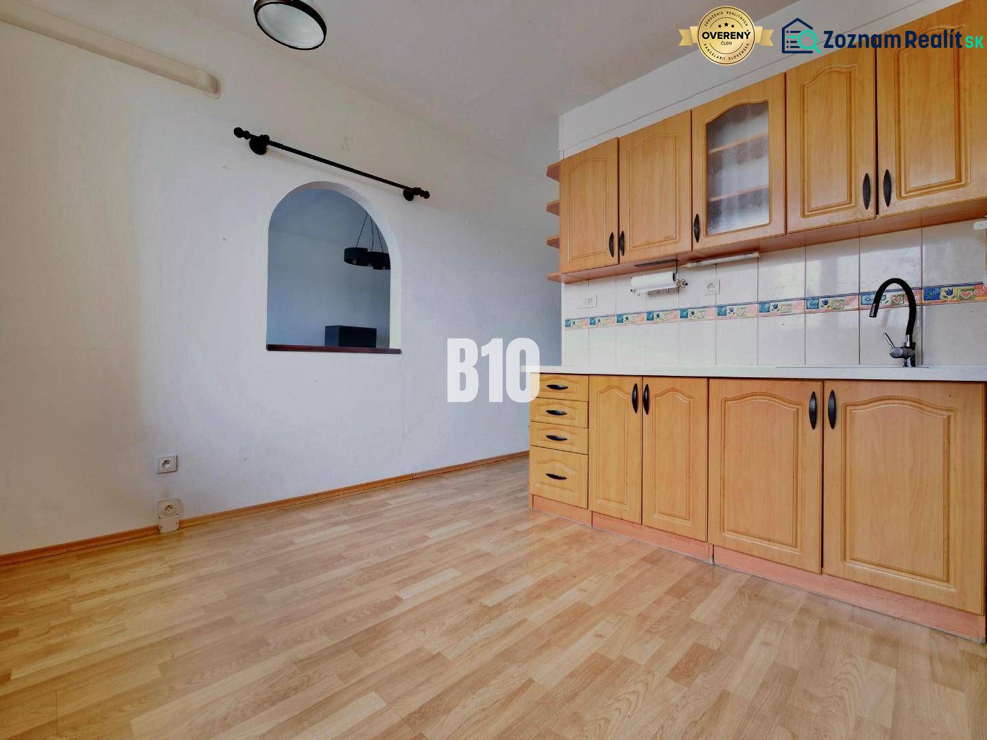 A kitchen in a 3-room apartment with a wooden decor floor and built-in cabinets.