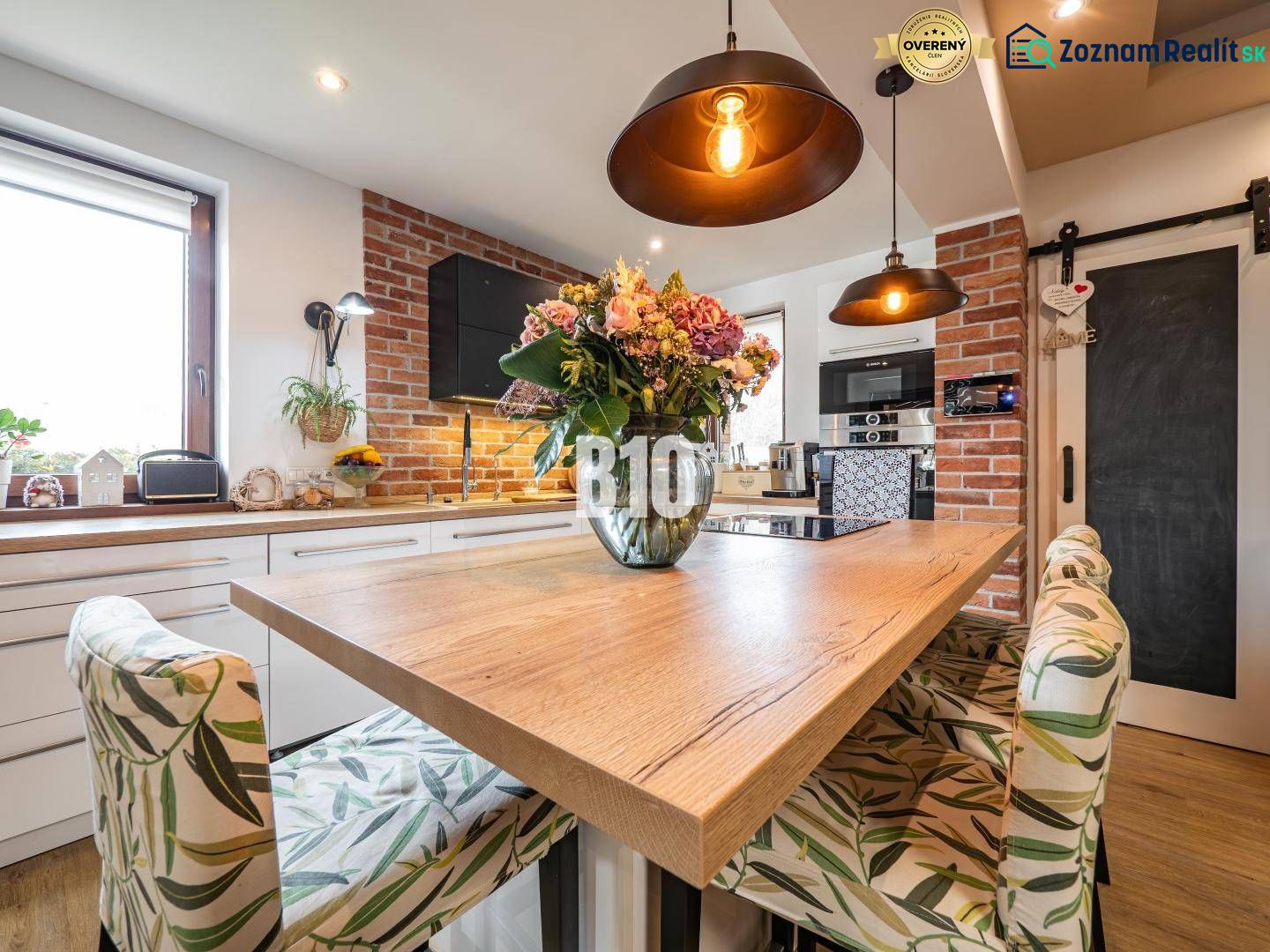 A kitchen in a family house with a dining table, a wooden decor floor, and brick cladding.