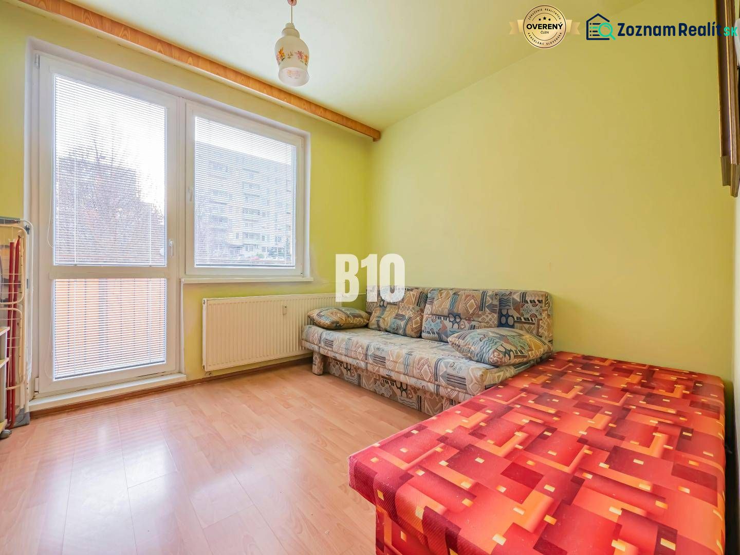 A room in a 3-room apartment with a sofa and a floor with a wood decor.