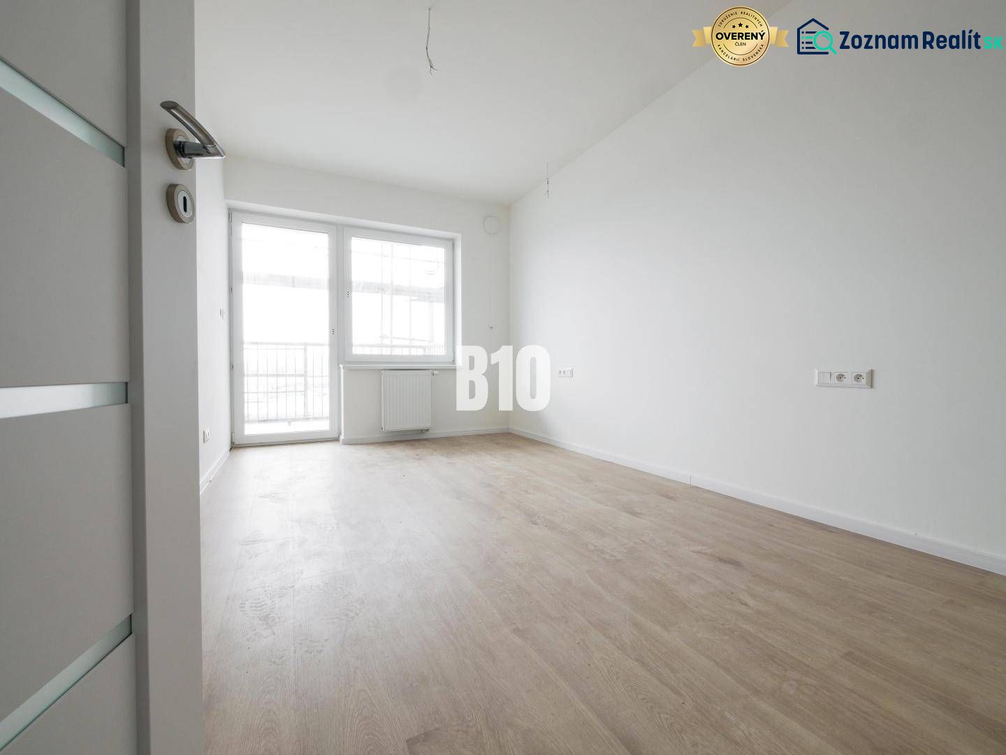 A spacious room with a large window, light flooring, and white walls in a 2-room apartment.