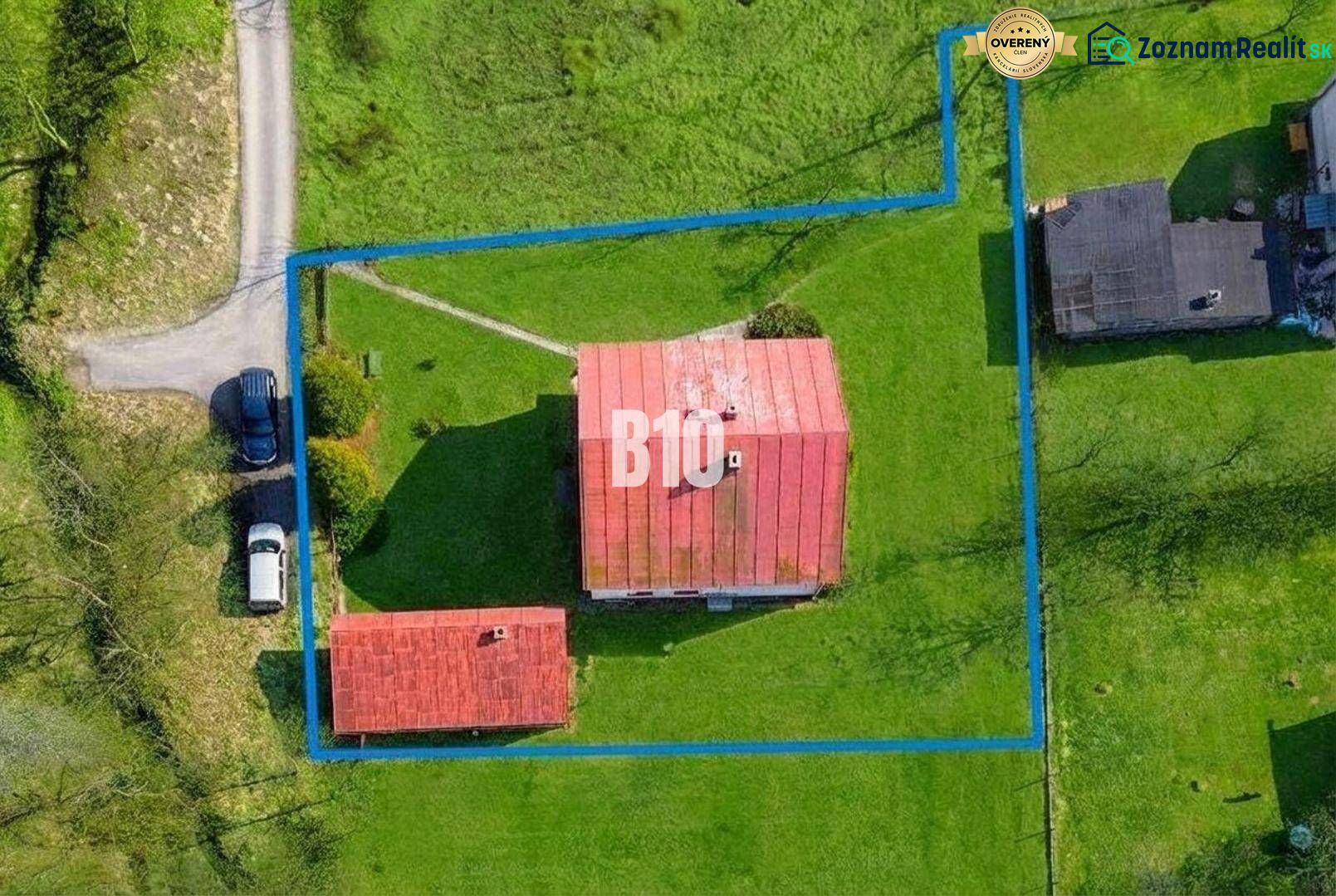 A family house in Raková with a fenced plot and adjacent buildings surrounded by greenery.