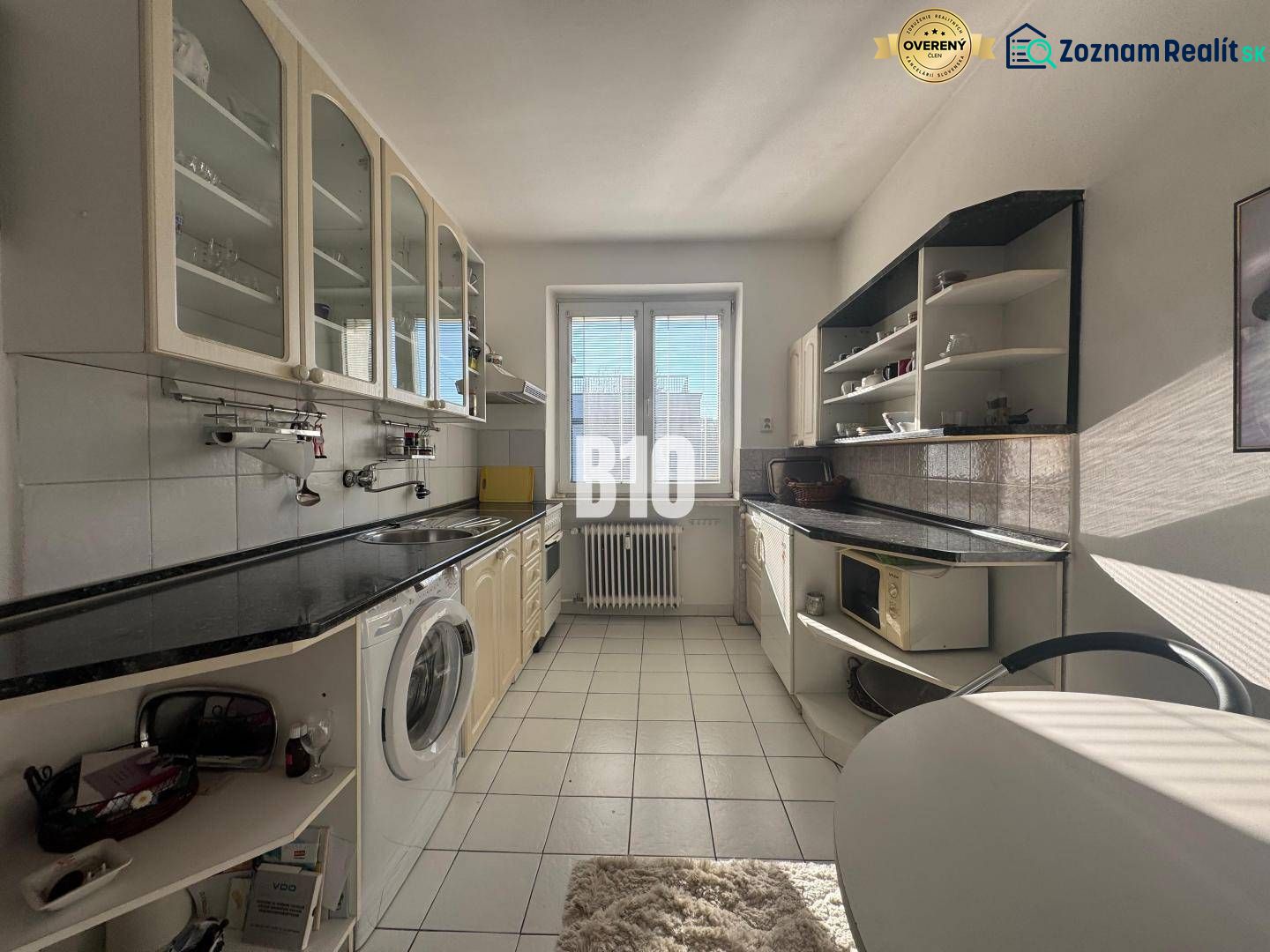 A kitchen in a 2-room apartment with white cabinets and a black countertop.