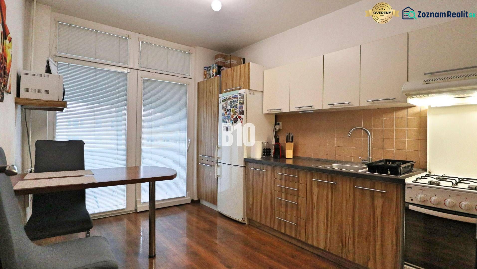 A kitchen in a 4-room apartment with a wood-patterned floor and a dining area.