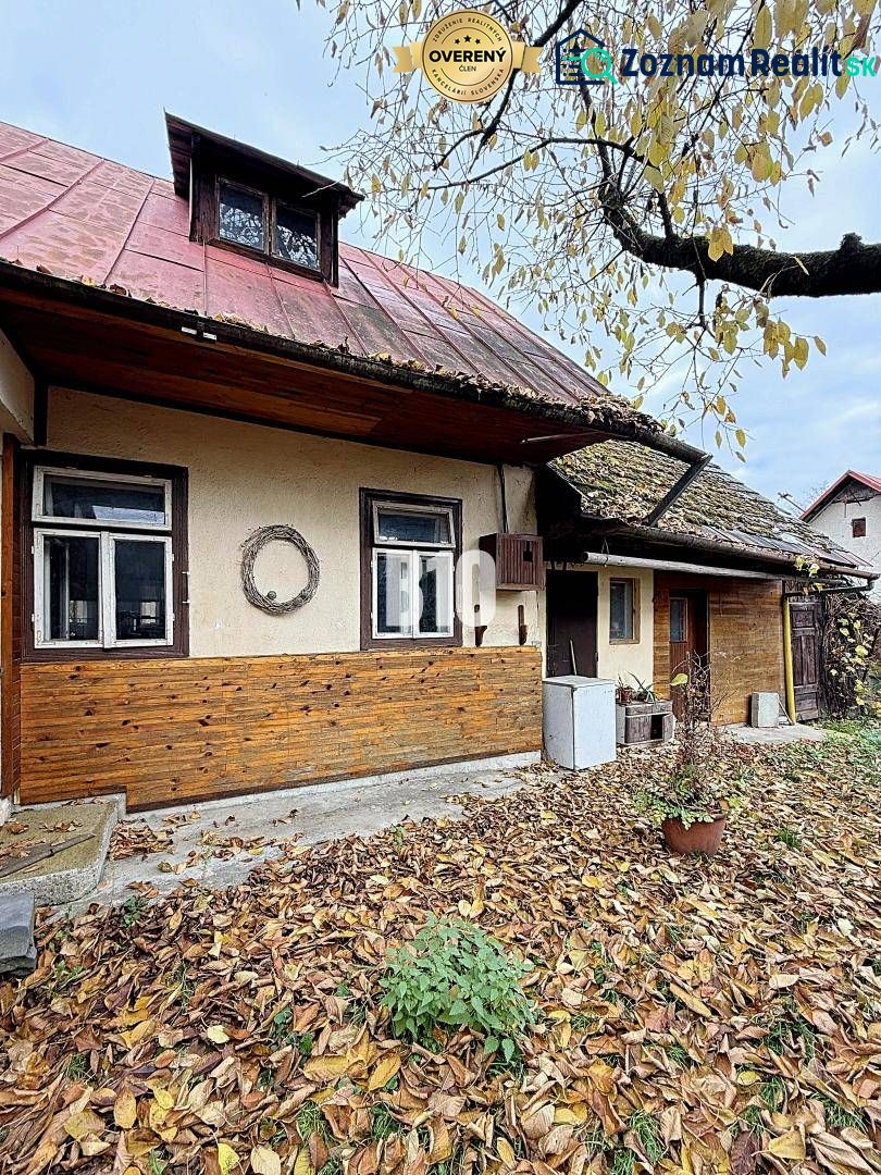 A family house in Kotešová with old wooden cladding and falling leaves in the garden.
