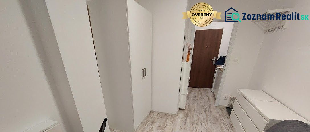Cozy studio apartment with white furniture and a wood-patterned floor.
