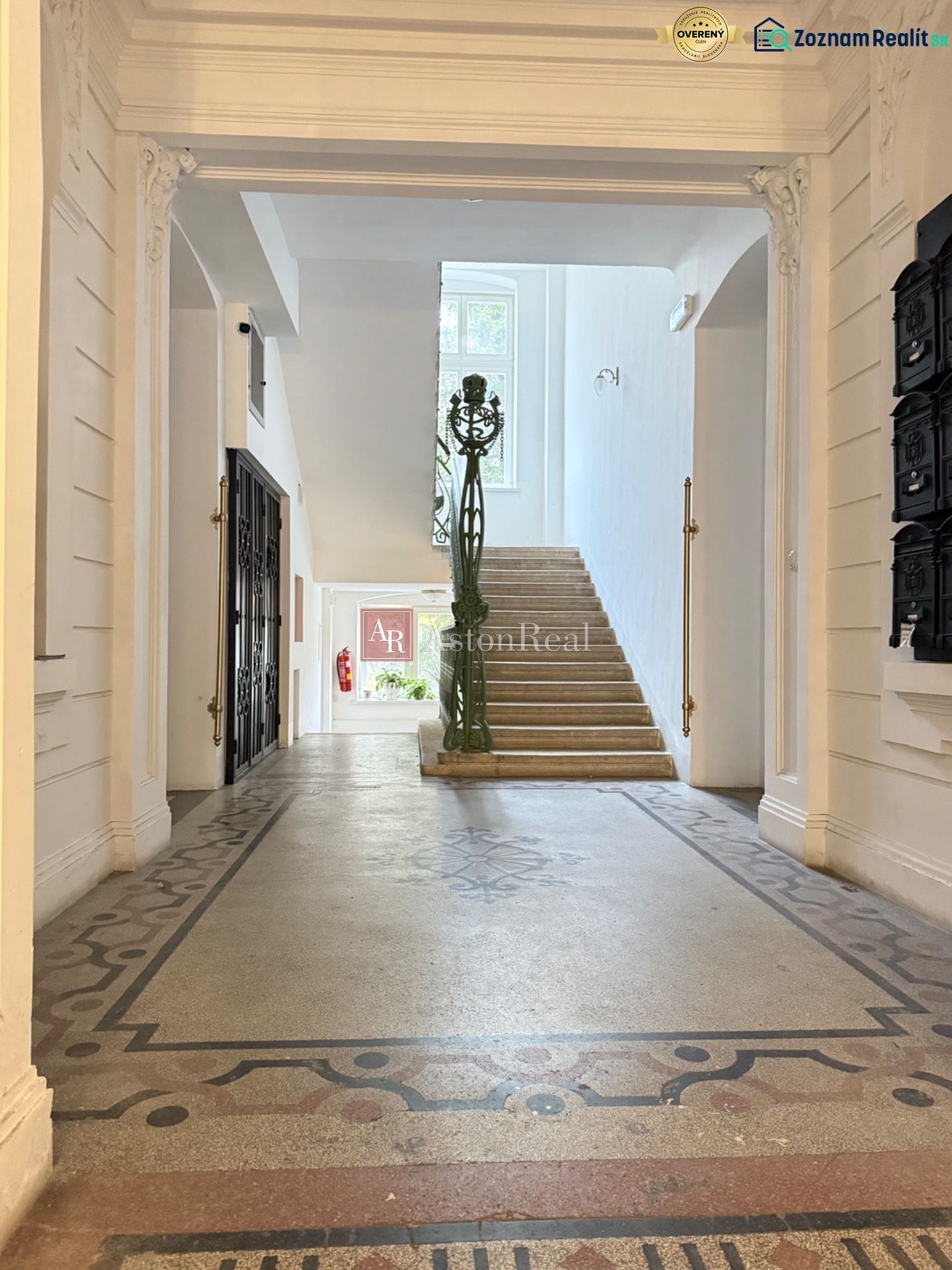 The entrance hall with a decorative floor leads to a staircase with a window.