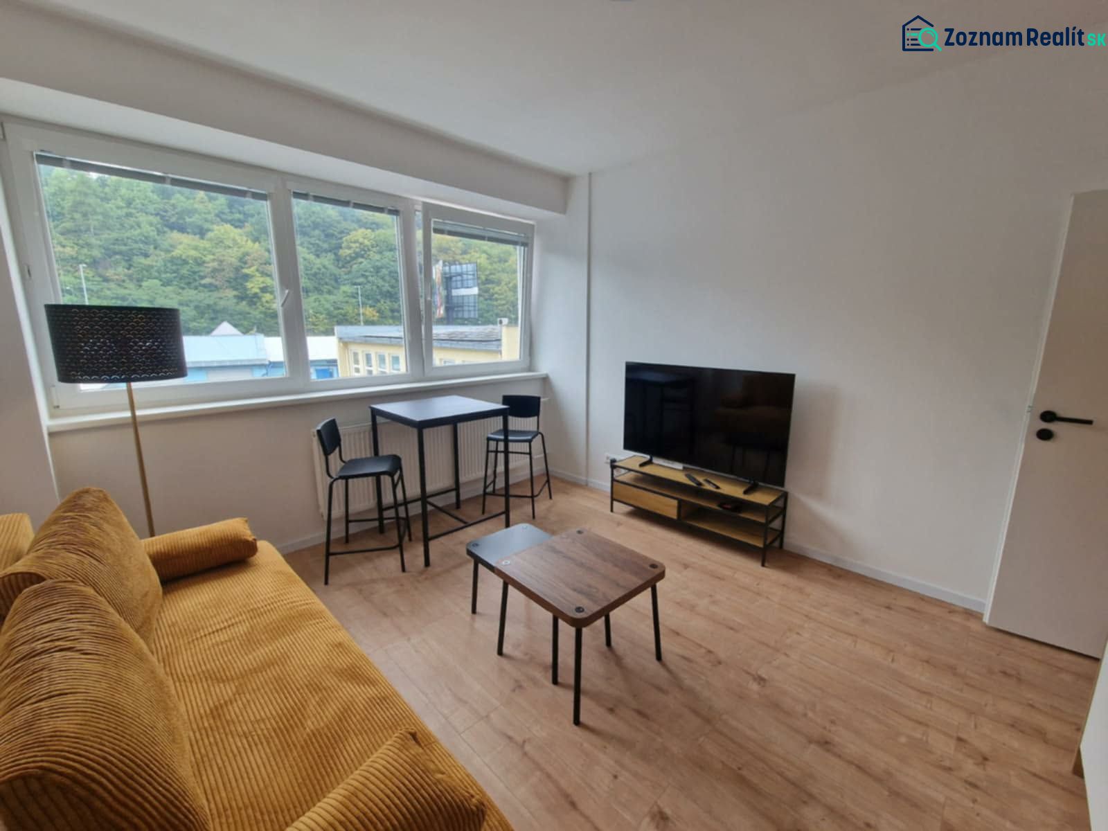 Living room with a sofa, television, and wooden decor flooring in a 2-room apartment.