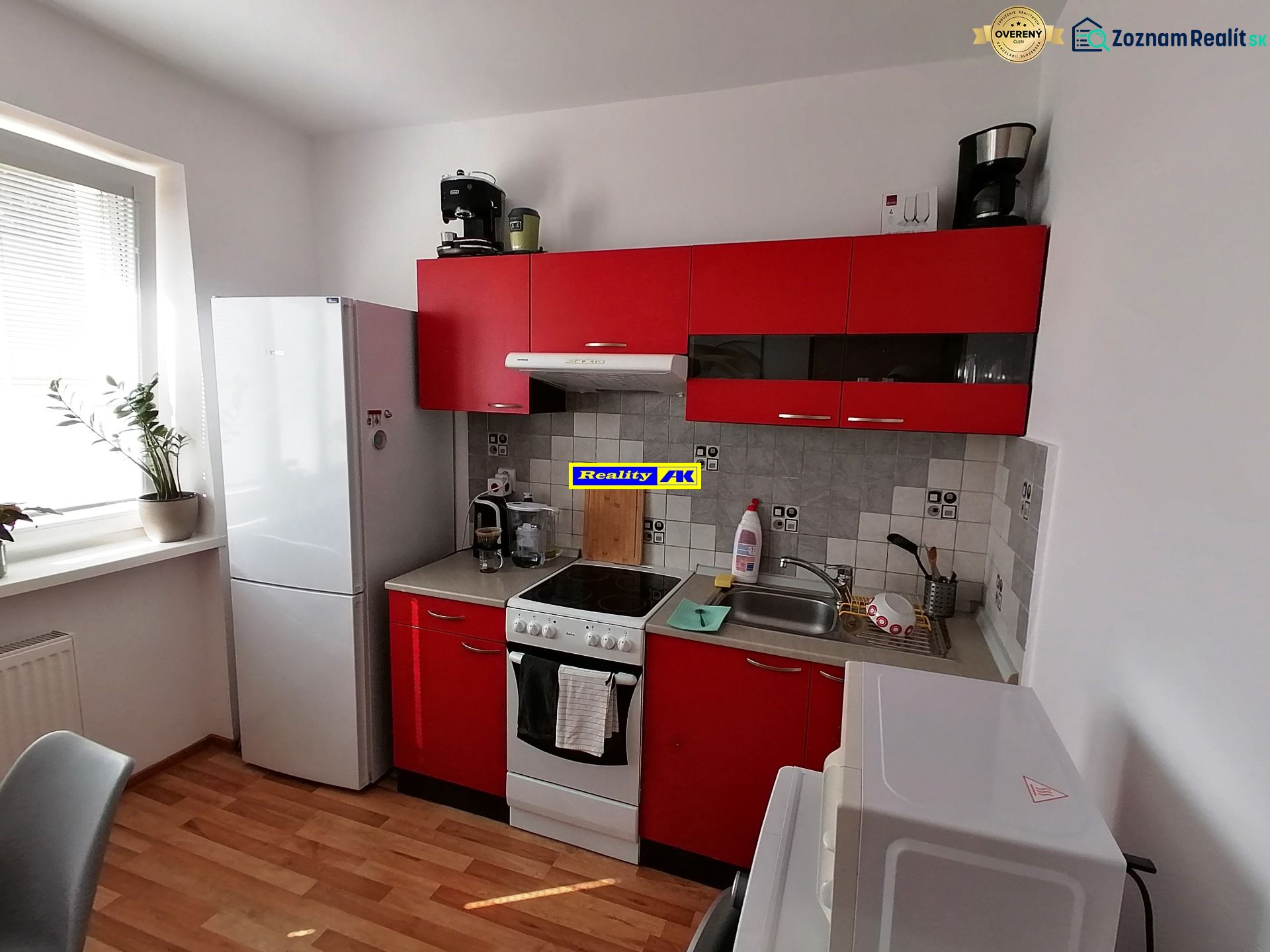 A kitchen with red cabinets and a wood-patterned floor in a studio apartment.