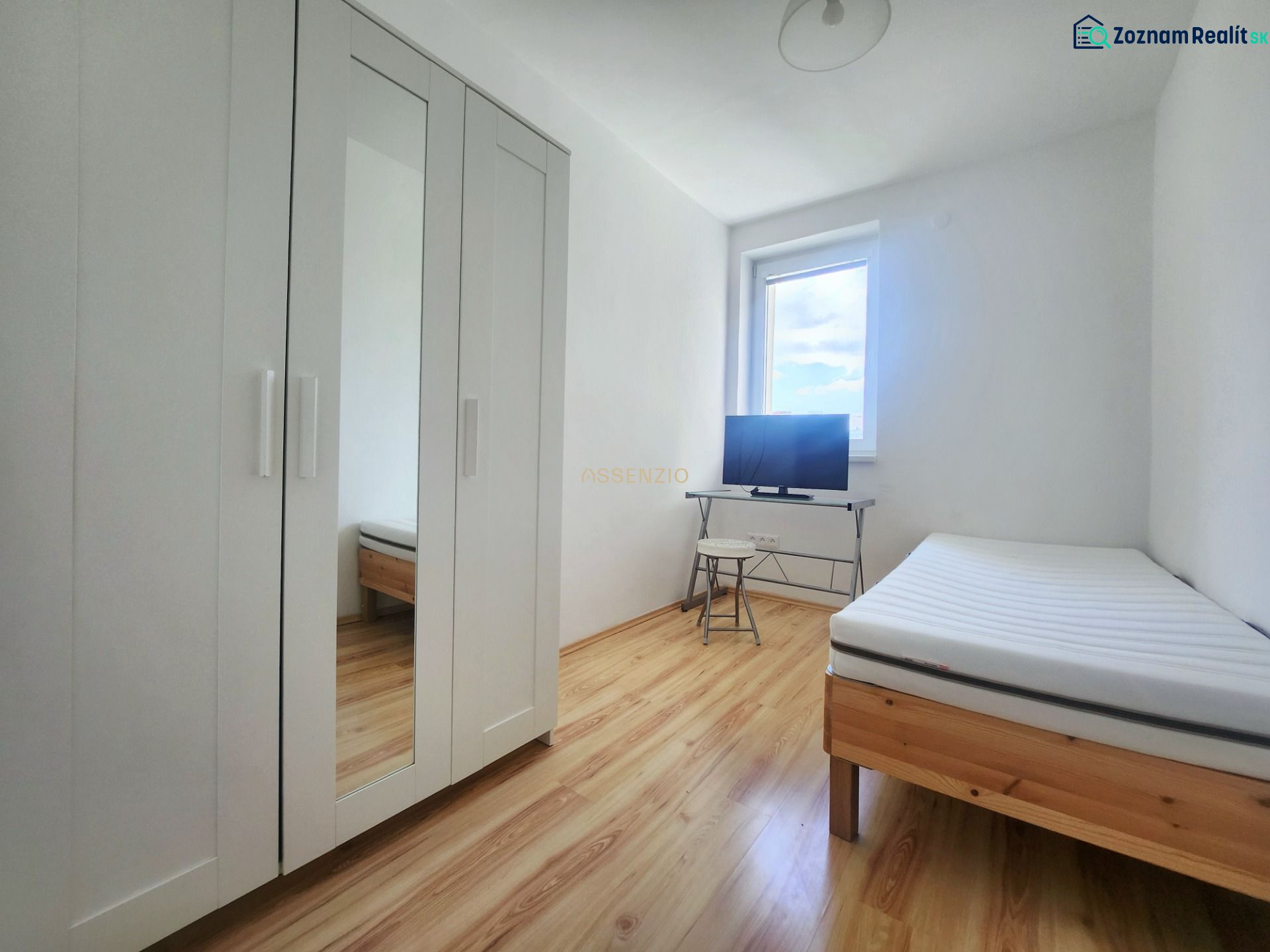 A bright room with a bed, a white wardrobe, and a television, a 3-room apartment, floor with wood decor.