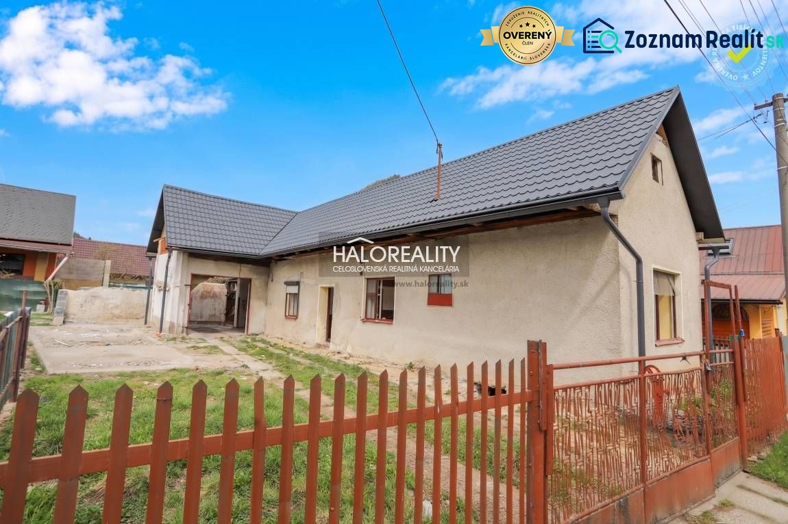 A family house in Stupno with a metal roof, two windows, and a solid fence.