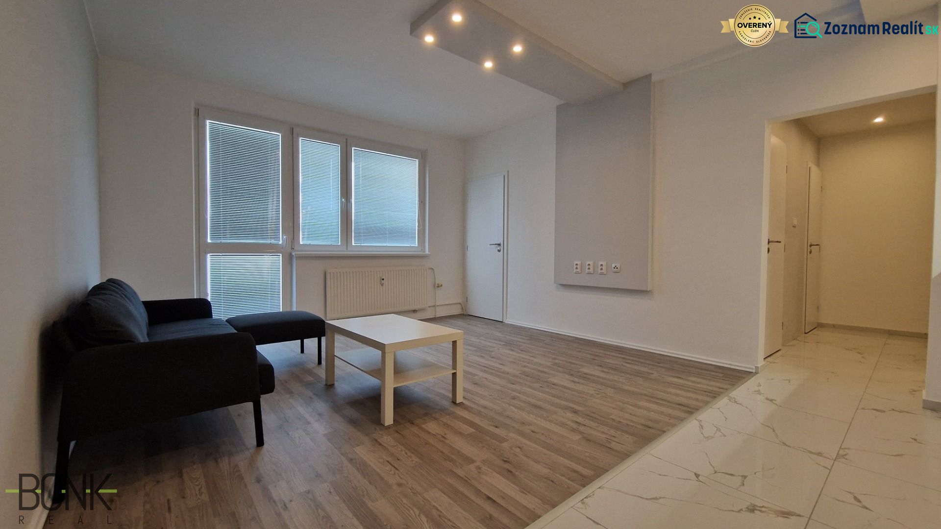 Living room in a two-room apartment with a wooden decor floor, sofa, and coffee table.