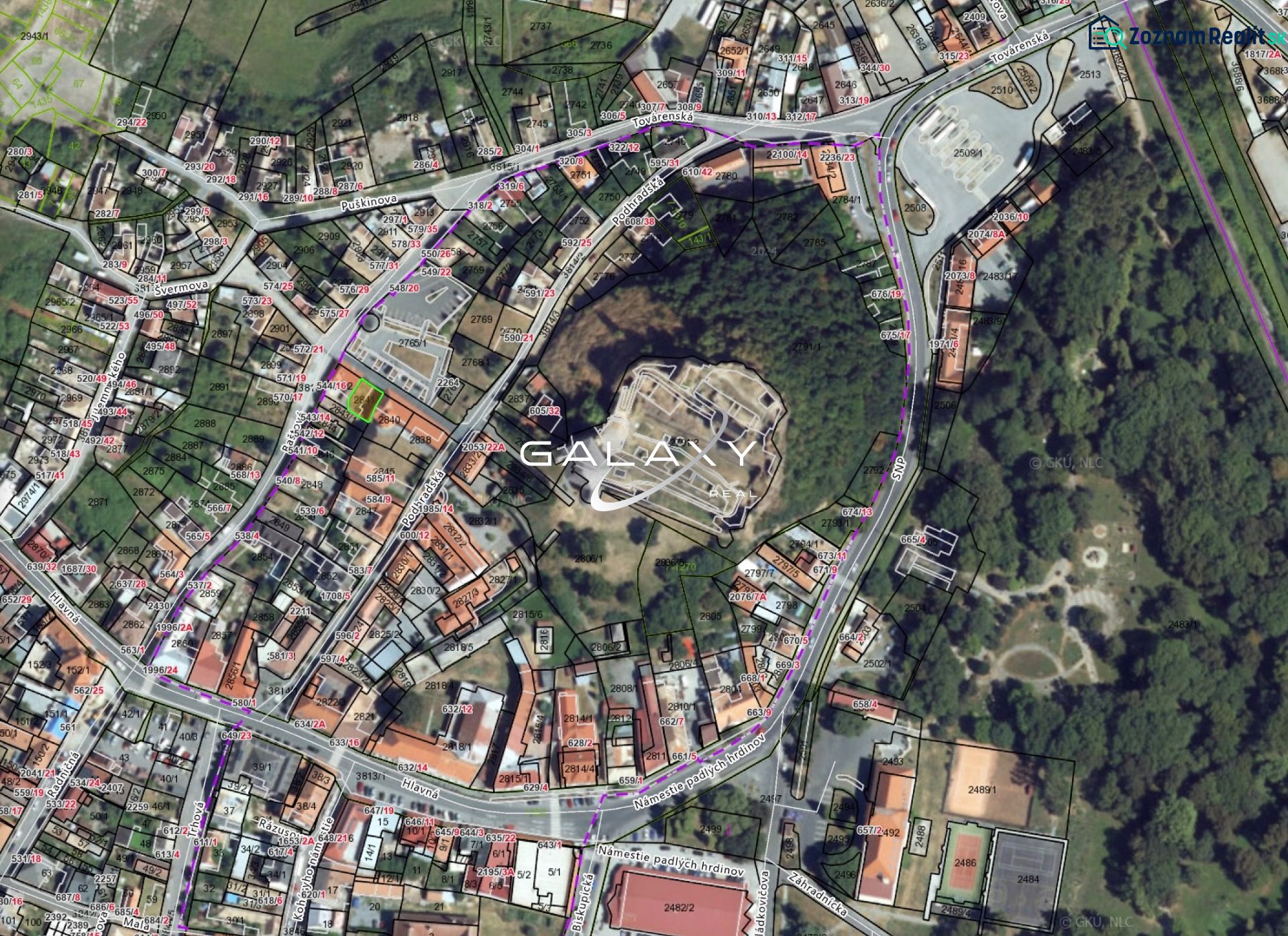 Aerial view of plots in the historical center of Fiľakovo, surrounded by buildings and greenery.