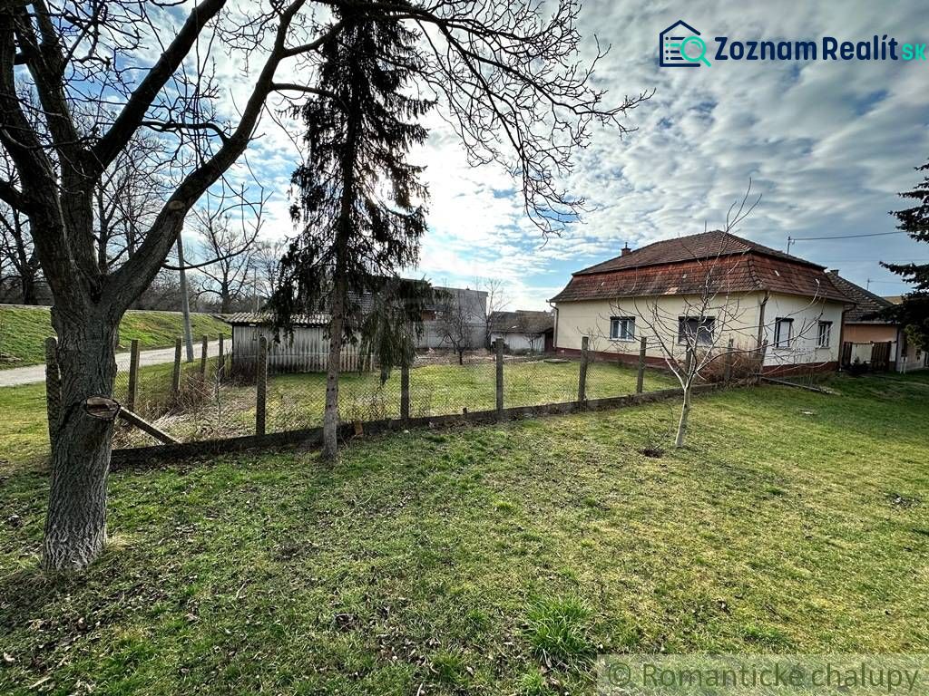 A family house in Kolárovo with a lawn and trees under a blue sky.