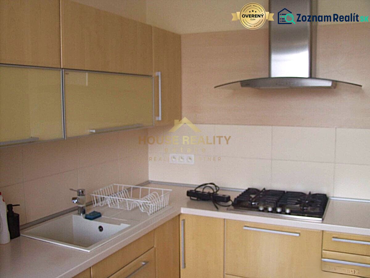 A kitchen in a 2-room apartment with a gas stove and an extractor hood, light cabinets.