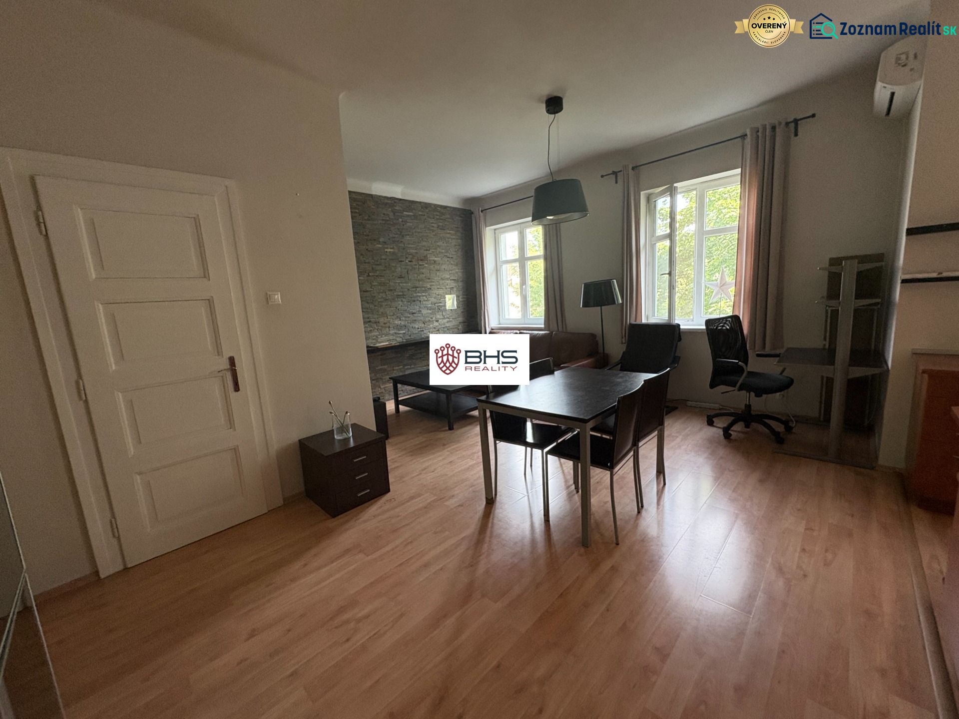 Interior of a 2-room apartment with a wooden decor floor, table, and chair.