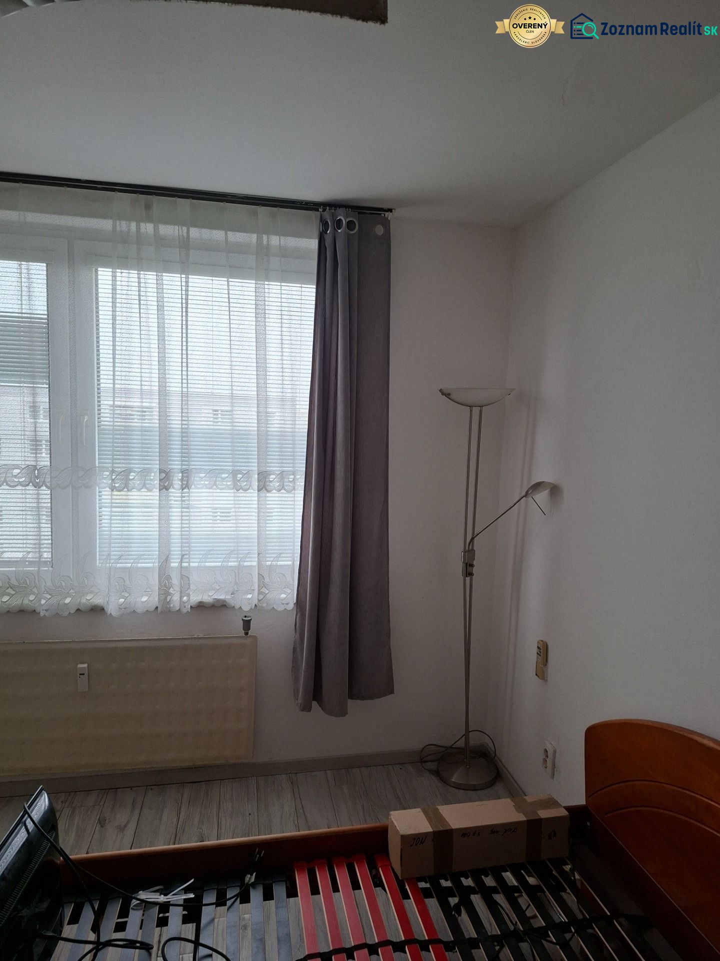 A room with a bed, windows, and a floor with wooden decor in a two-room apartment.