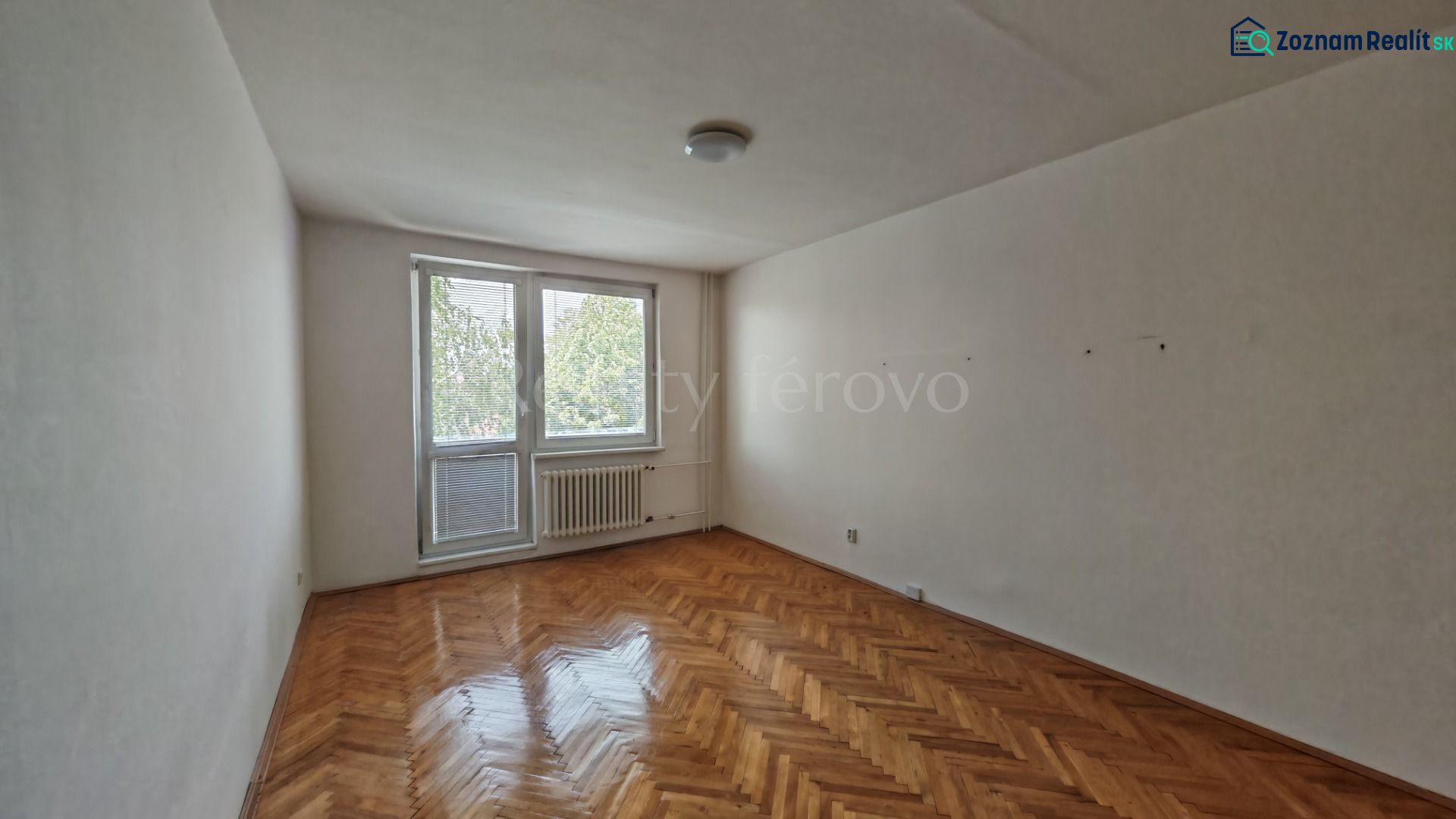 Living room in a two-room apartment with a wooden decor floor and a balcony.