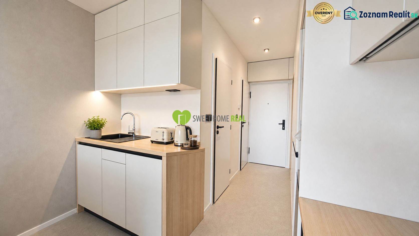 A kitchen in a 2-room apartment with white cabinets and a wooden decor.