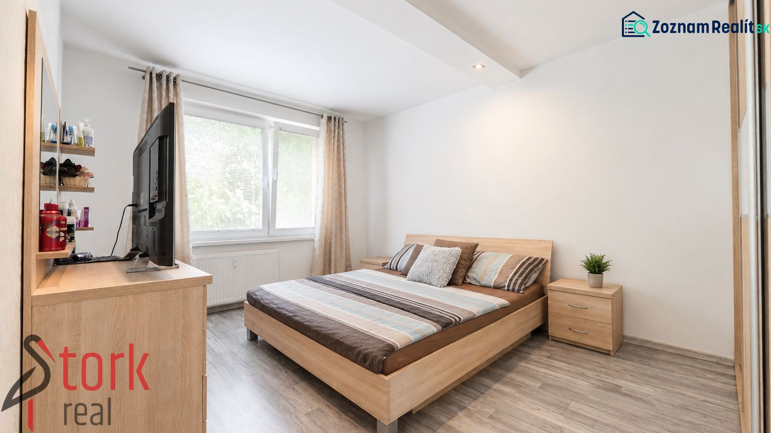 A bright bedroom with a bed and a wooden decor floor in a 3-room apartment.