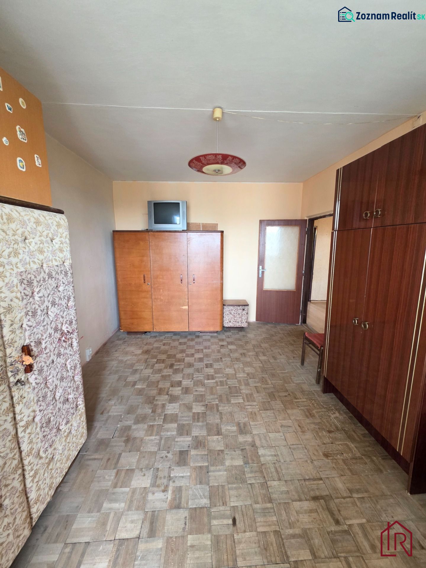 A room in a 3-room apartment with a wooden decor floor and older furniture.