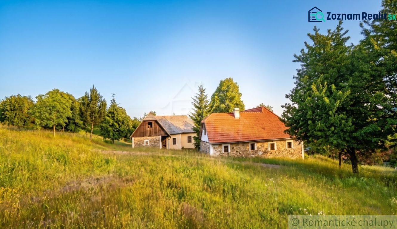 A rural scene by a family house in Budiná surrounded by greenery and trees.