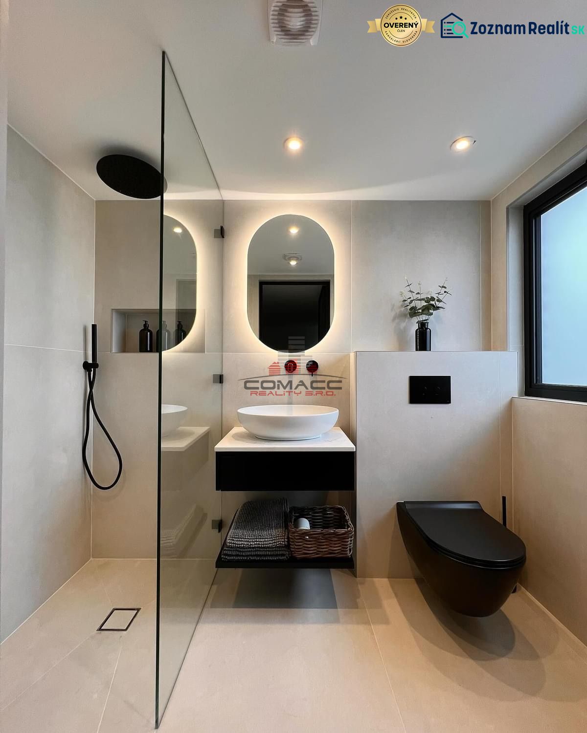 A bathroom in a family house with an oval mirror, a sink, and a black shower enclosure.