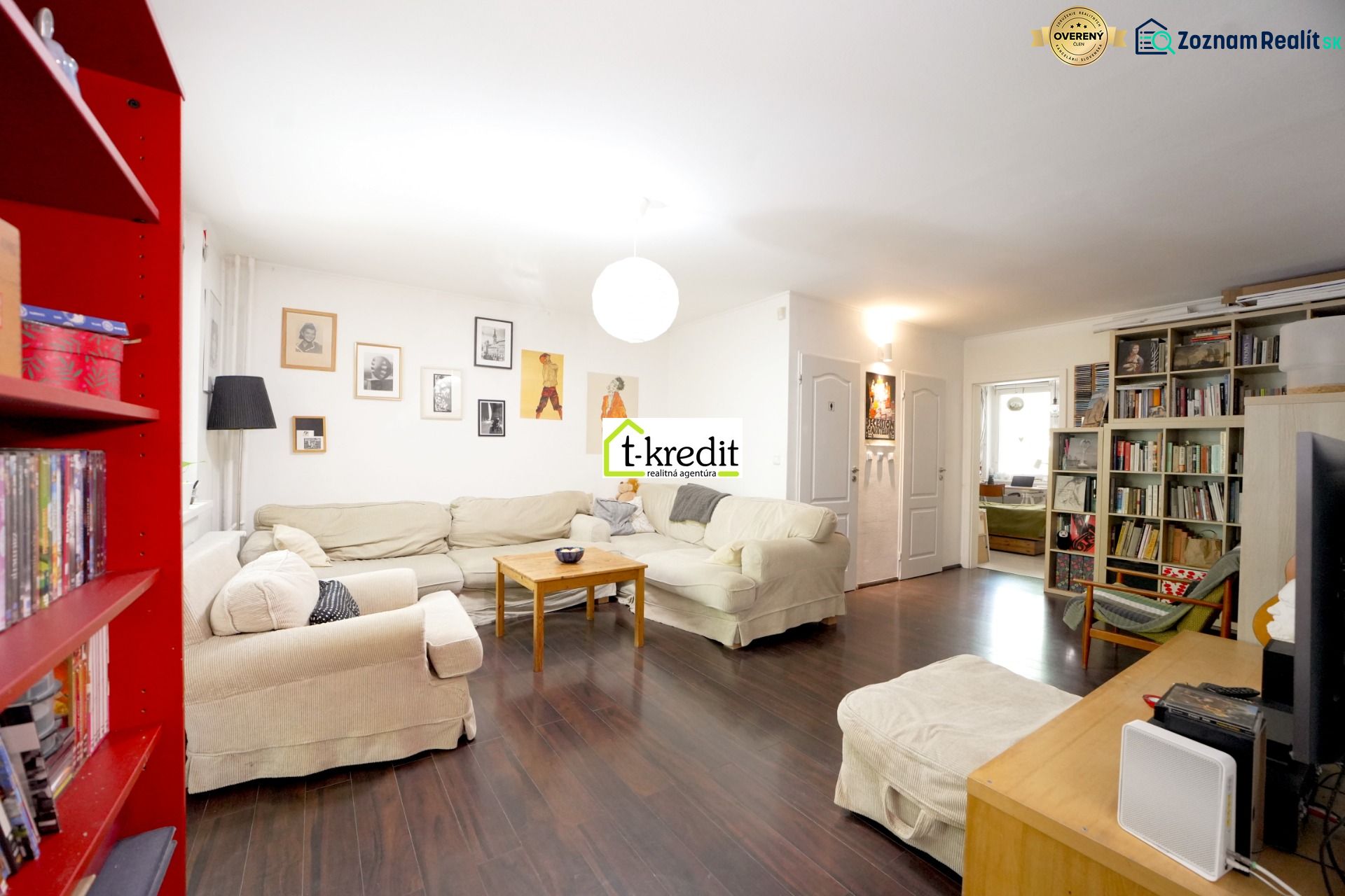Living room in a 3-room apartment with a sofa, bookshelf, and wooden decor flooring.