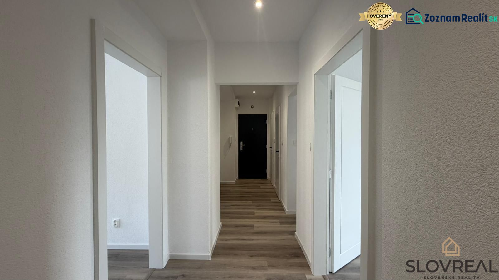 A hallway in a 3-room apartment with a wooden decor floor and white walls.