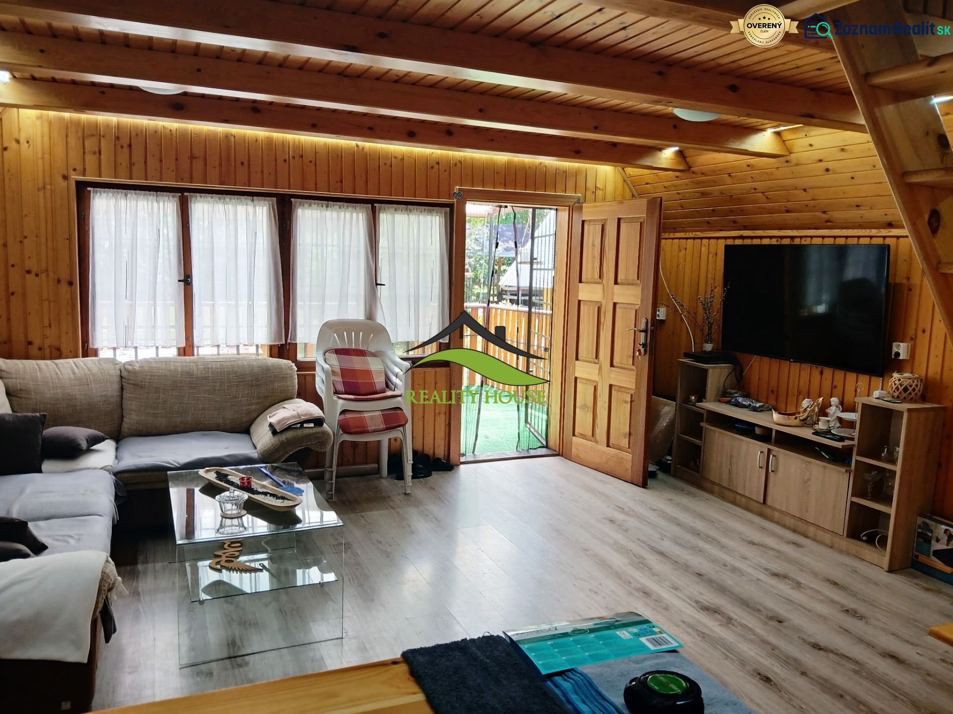 The interior of a cabin with a comfortable couch, television, and a wooden decor floor.