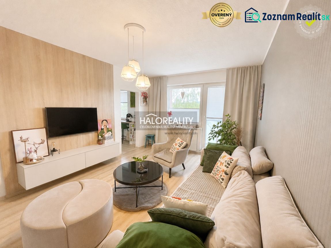 Living room of a two-room apartment with a wooden decor floor, a comfortable sofa, and a television.