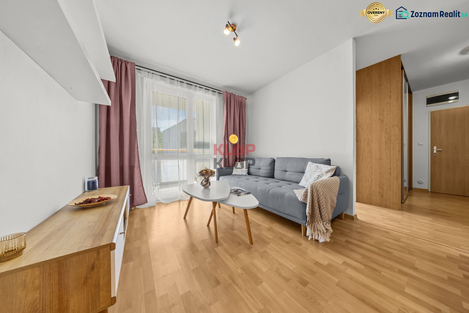 Living room with wood-patterned flooring, a sofa, and a coffee table in a three-room apartment.