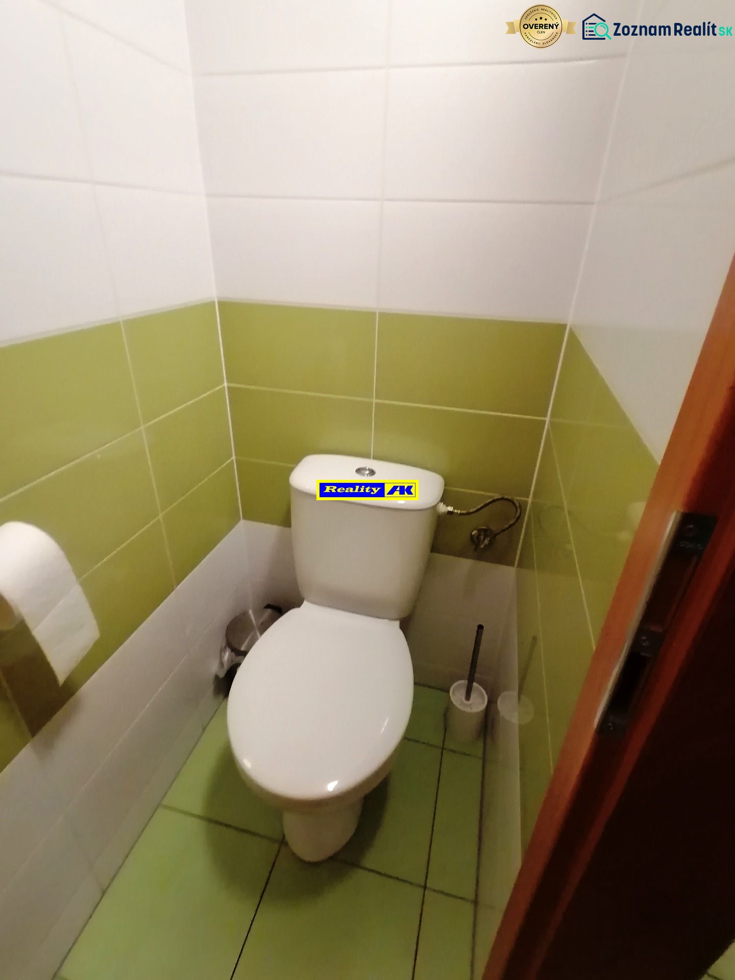 A toilet with white and green tiles in commercial premises.