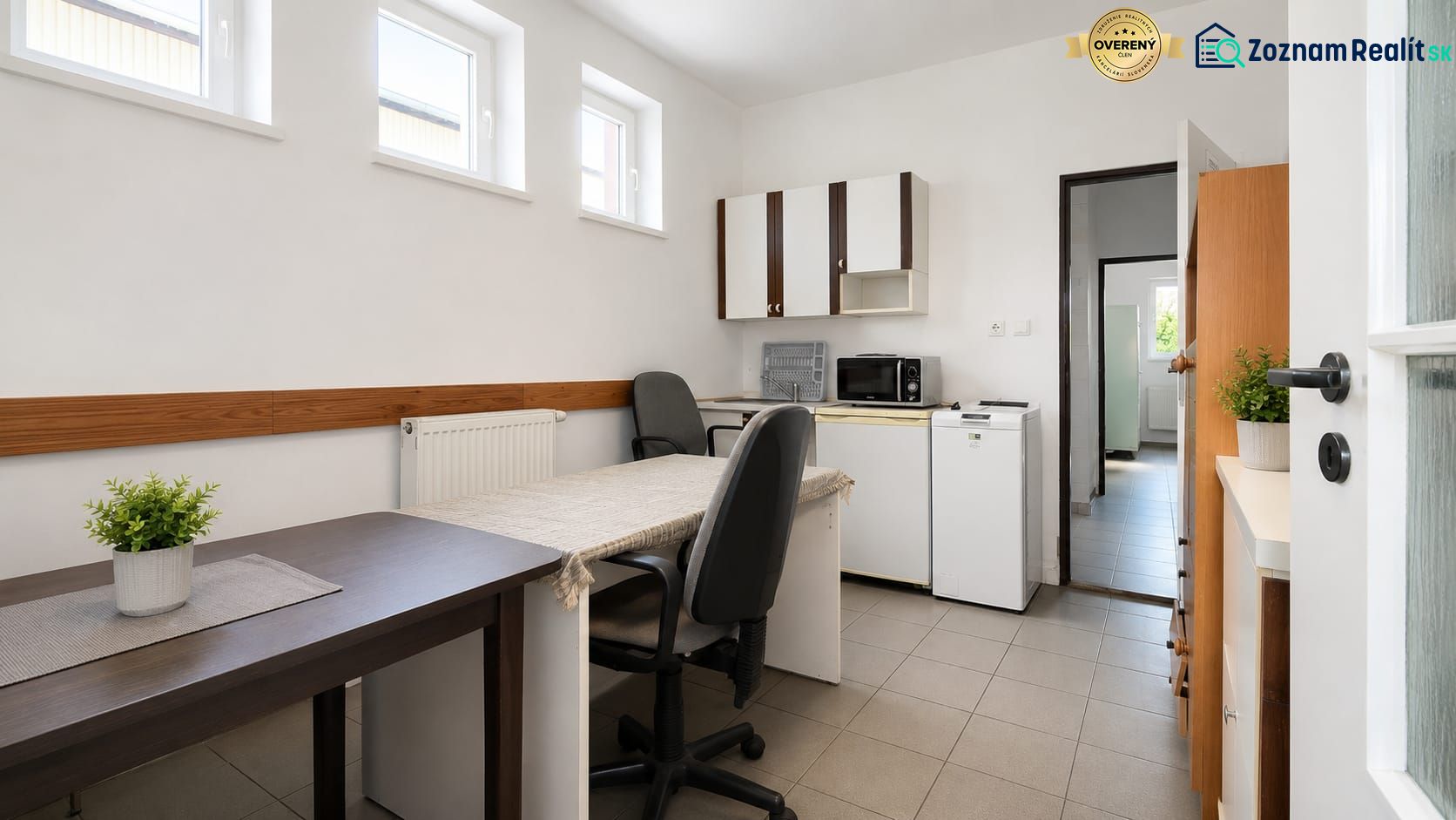 Interior of a warehouse and hall with an office, table, chairs, and kitchen appliances.